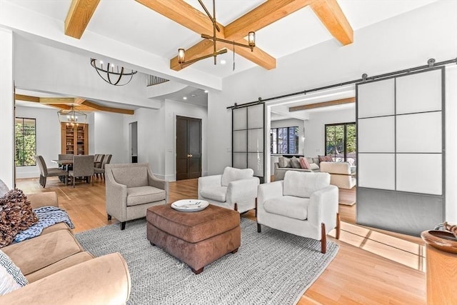 living room with beamed ceiling, a barn door, and light hardwood / wood-style flooring