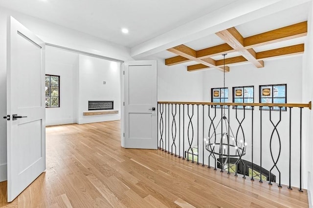 corridor featuring coffered ceiling, beam ceiling, light hardwood / wood-style floors, and a chandelier