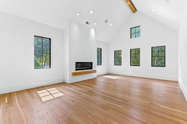 unfurnished living room featuring beamed ceiling, high vaulted ceiling, and light wood-type flooring