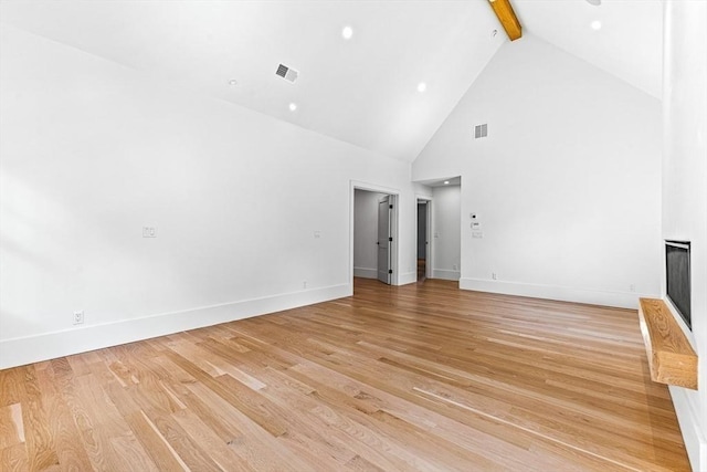 unfurnished living room with high vaulted ceiling, beamed ceiling, and light wood-type flooring