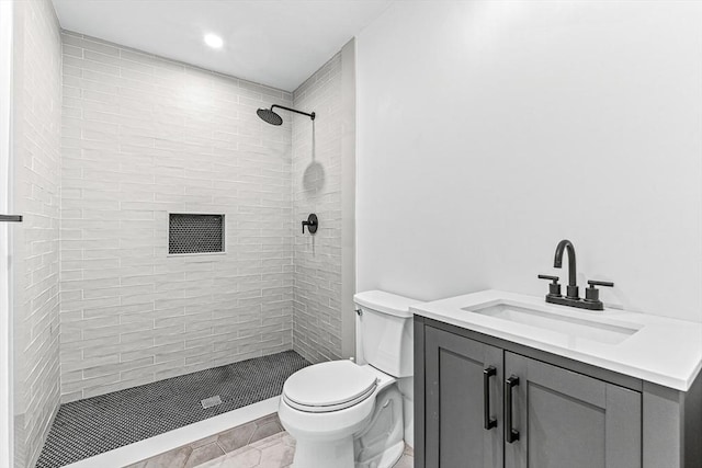 bathroom with tiled shower, vanity, and toilet