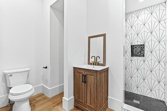 bathroom with hardwood / wood-style flooring, vanity, a shower, and toilet