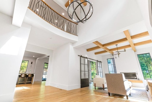 living room with a healthy amount of sunlight, coffered ceiling, beam ceiling, and light wood-type flooring