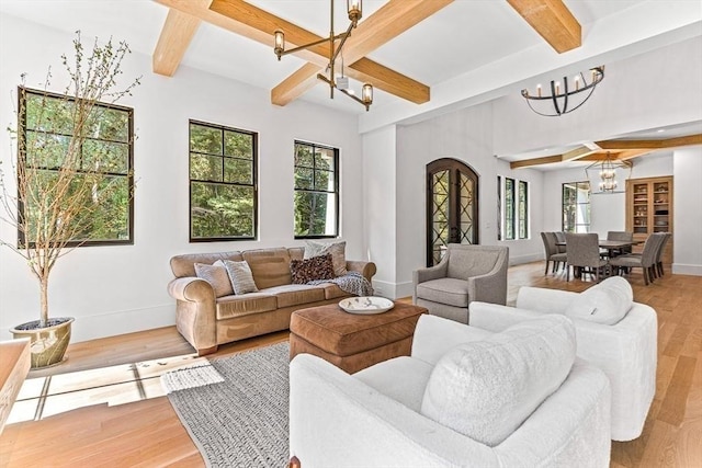 living room with an inviting chandelier, beamed ceiling, a healthy amount of sunlight, and light wood-type flooring