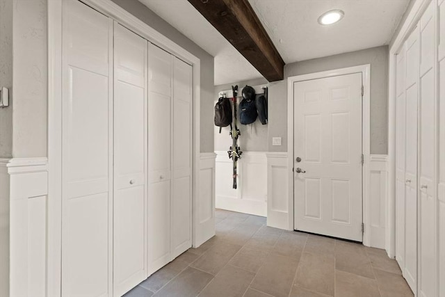 18 Sunset Dr, Sharon, MA 02067 - corridor with beamed ceiling, light tile patterned flooring, a wainscoted wall, and a decorative wall