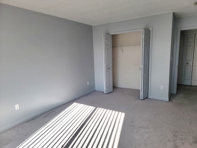 unfurnished bedroom featuring light colored carpet and a closet