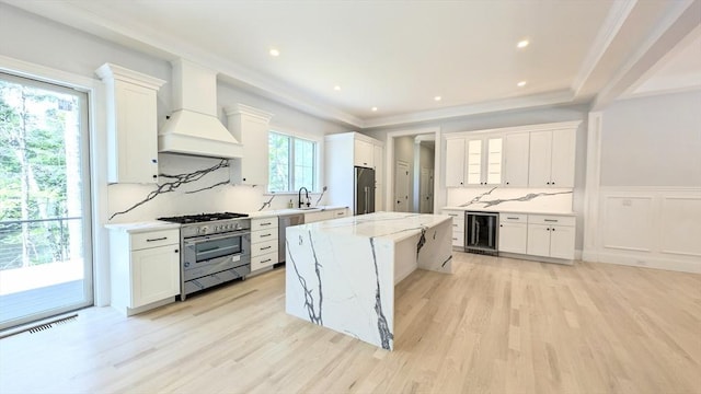 784 Main St, Hudson, MA 01749 - kitchen featuring stainless steel appliances, wine cooler, light wood finished floors, a center island, and white cabinetry