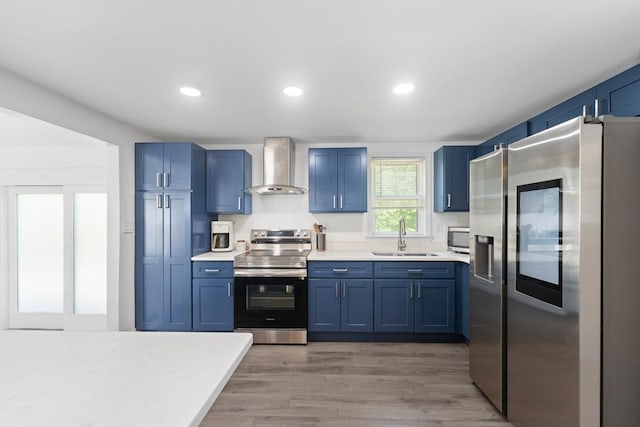 5 Woodland Dr, Oxford, MA 01540 - kitchen with stainless steel appliances, wall chimney exhaust hood, blue cabinetry, light countertops, and light wood-style floors