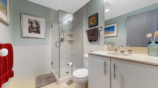 bathroom with vanity, a shower stall, tile walls, toilet, and tile patterned floors