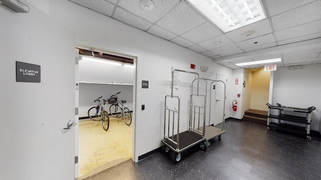 exercise room featuring a drop ceiling and baseboards