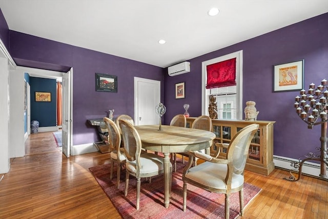 dining area featuring a wall mounted air conditioner, wood-type flooring, and baseboard heating