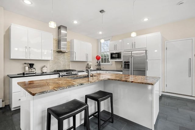 kitchen with stainless steel appliances, white cabinetry, a kitchen island with sink, and wall chimney exhaust hood