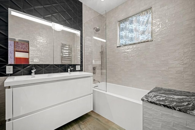 bathroom featuring vanity, tiled shower / bath combo, hardwood / wood-style floors, and tile walls