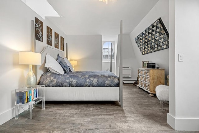 bedroom featuring wood-type flooring, a baseboard heating unit, and a wall mounted air conditioner