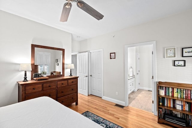 bedroom featuring a ceiling fan, visible vents, baseboards, light wood finished floors, and ensuite bath