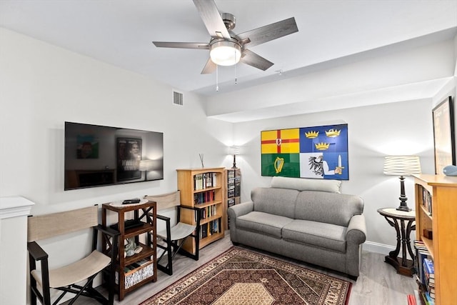 living area with baseboards, a ceiling fan, wood finished floors, and visible vents