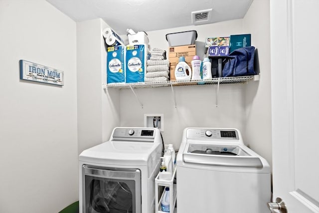 washroom with visible vents, laundry area, and washing machine and clothes dryer