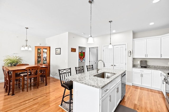kitchen with appliances with stainless steel finishes, a breakfast bar, a sink, white cabinetry, and light wood-type flooring