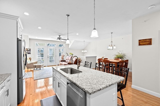 kitchen with a ceiling fan, open floor plan, a breakfast bar area, a sink, and stainless steel appliances