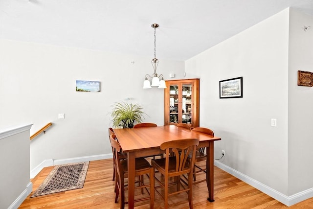 dining space with baseboards, a chandelier, light wood-style flooring, and visible vents