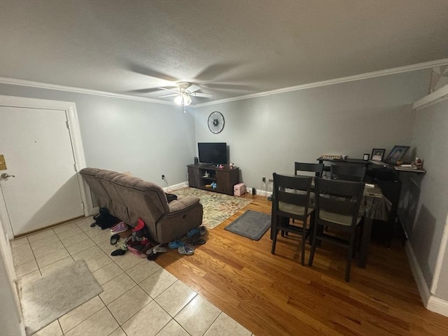 living room featuring light wood-style floors, crown molding, baseboards, and a ceiling fan