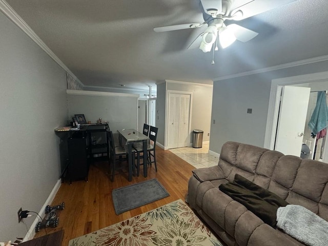 living area with ceiling fan, ornamental molding, wood finished floors, and baseboards