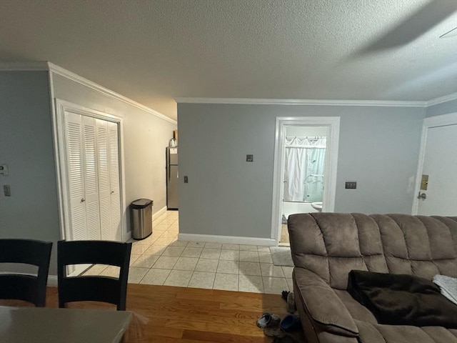 living room with a textured ceiling, baseboards, crown molding, and light tile patterned flooring