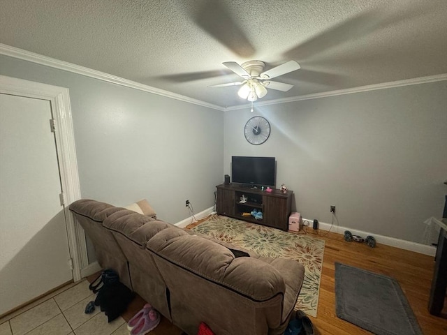 living room featuring baseboards, ceiling fan, ornamental molding, wood finished floors, and a textured ceiling