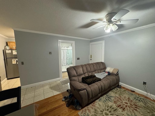 living area featuring ornamental molding, a textured ceiling, baseboards, and light tile patterned floors