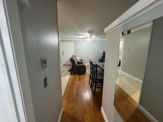 corridor featuring ornamental molding, wood finished floors, and baseboards