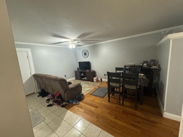 living room featuring baseboards, a ceiling fan, ornamental molding, a textured ceiling, and light wood-style floors