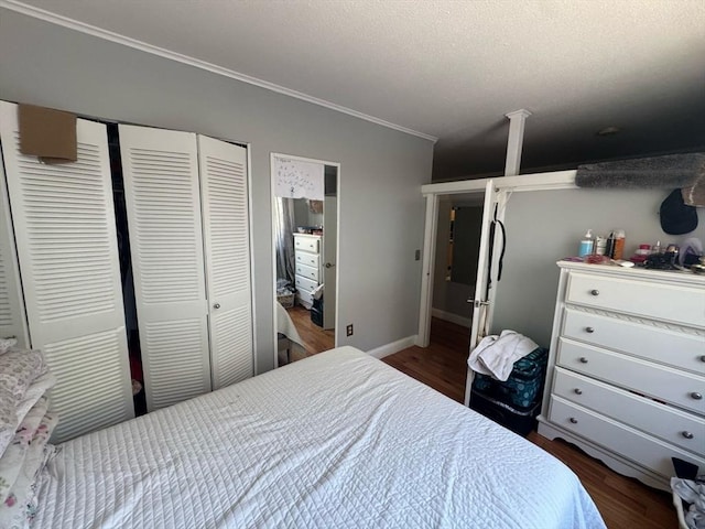 bedroom with a textured ceiling, wood finished floors, baseboards, ornamental molding, and a closet