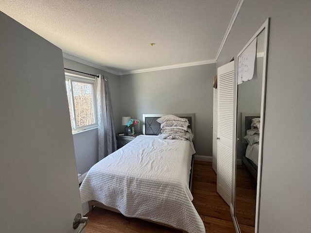 bedroom featuring ornamental molding, a textured ceiling, baseboards, and wood finished floors