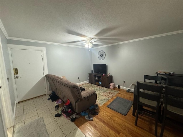 living room with a ceiling fan, ornamental molding, light wood-style floors, and a textured ceiling