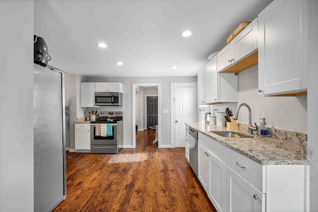 kitchen with light stone counters, sink, dark wood-type flooring, white cabinetry, and appliances with stainless steel finishes