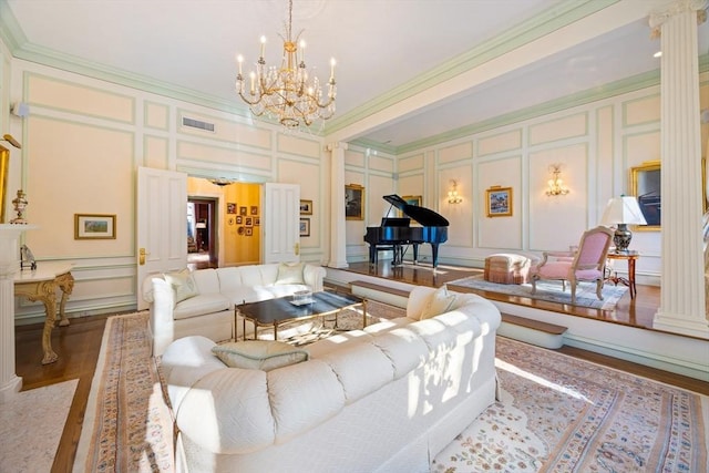 living room with ornate columns, hardwood / wood-style floors, ornamental molding, and a notable chandelier