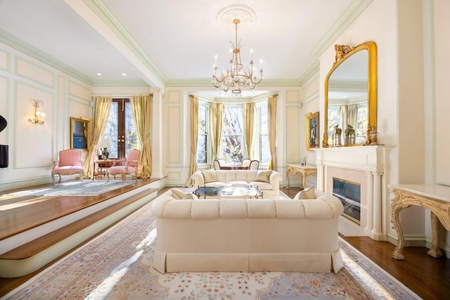 sitting room featuring hardwood / wood-style floors, a premium fireplace, a chandelier, and ornamental molding