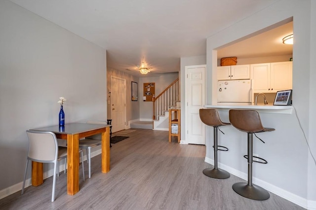 1 Riverview Blvd Unit 2-213, Methuen, MA 01844 - kitchen with white fridge, a breakfast bar, baseboards, and light wood finished floors