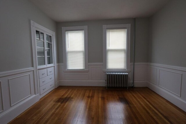 15-1/2 Tremlett St, Boston, MA 02124 - unfurnished room featuring radiator, healthy amount of natural light, dark wood-type flooring, wainscoting, and a decorative wall