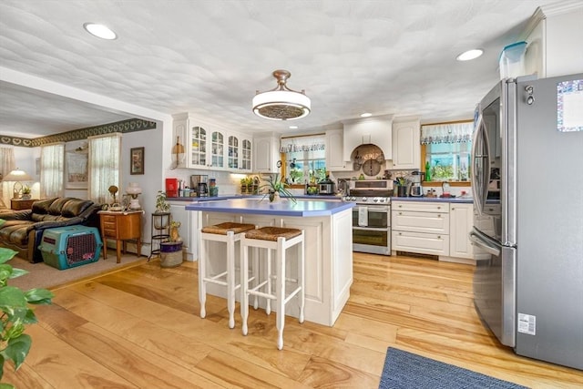 67 Main St, Atkinson, NH 03811 - kitchen with appliances with stainless steel finishes, white cabinetry, dark countertops, a kitchen bar, and glass insert cabinets