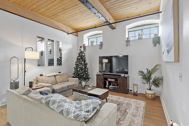 living room with light hardwood / wood-style floors, beamed ceiling, a high ceiling, and wood ceiling