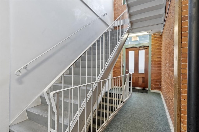 stairs featuring brick wall and carpet flooring