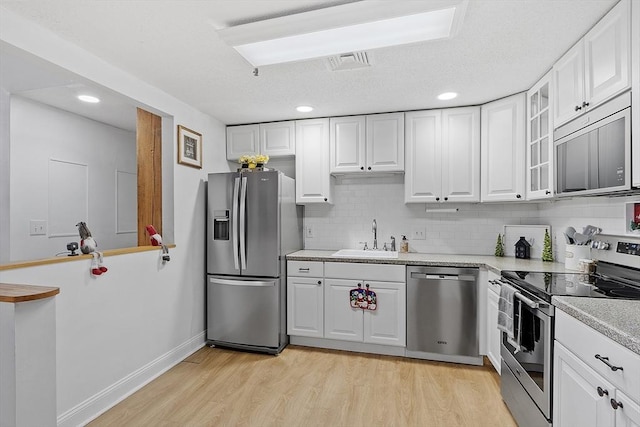 kitchen featuring white cabinets, stainless steel appliances, decorative backsplash, and sink