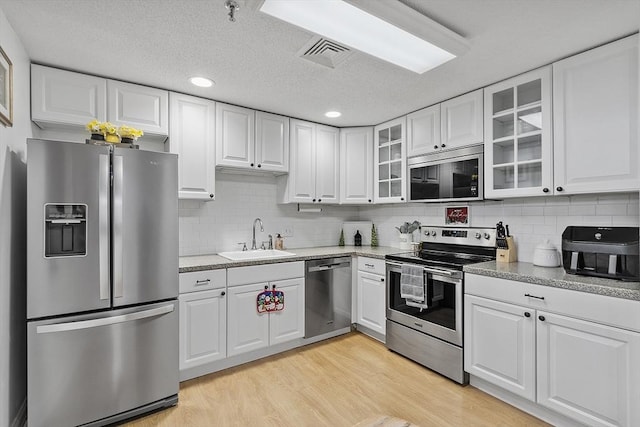 kitchen with light hardwood / wood-style floors, sink, white cabinetry, and appliances with stainless steel finishes