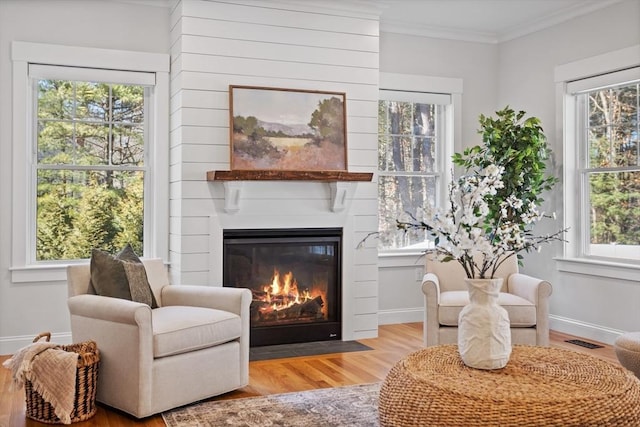 living area featuring plenty of natural light, a fireplace, visible vents, and ornamental molding