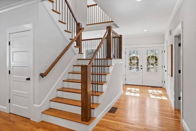 foyer entrance with visible vents, crown molding, light wood-type flooring, recessed lighting, and french doors