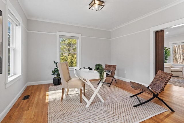 interior space featuring visible vents, baseboards, wood finished floors, and crown molding