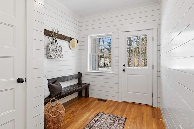 mudroom with crown molding, light wood-style floors, and visible vents