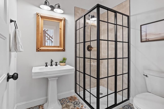 bathroom with a stall shower, toilet, and baseboards