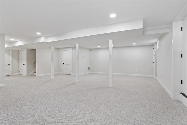 finished below grade area featuring light carpet, stairway, recessed lighting, and baseboards